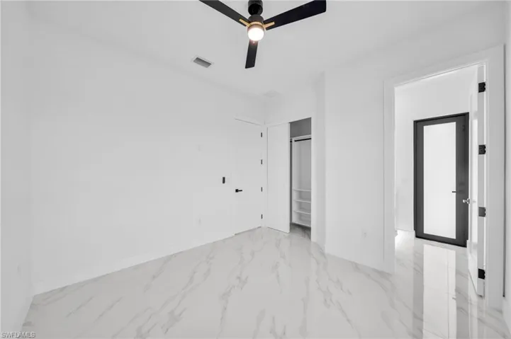 Unfurnished bedroom with light marble finish flooring, baseboards, and a ceiling fan