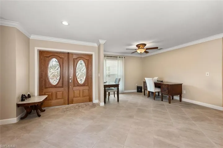 Entryway with light tile patterned floors, a ceiling fan, baseboards, and ornamental molding