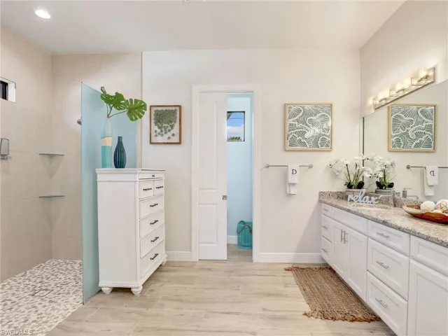 Bathroom featuring tiled shower and vanity