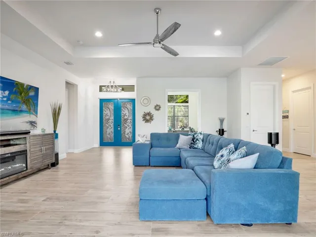 Living room with french doors, ceiling fan, a raised ceiling, and light hardwood / wood-style flooring