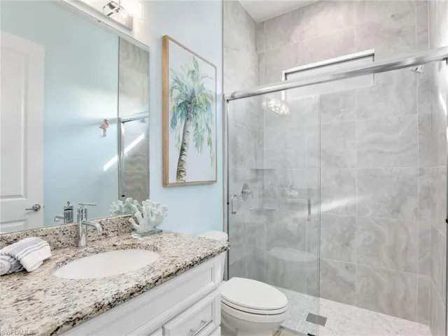 Bathroom with vanity, toilet, and a shower with door