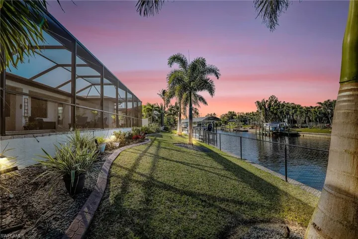 Yard at dusk featuring a lanai and a water view
