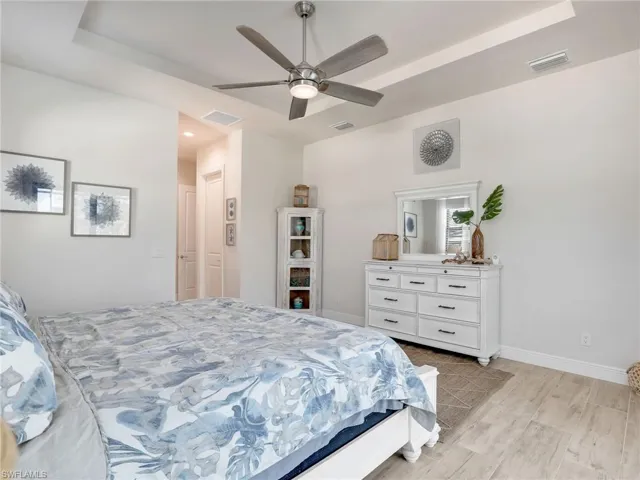 Bedroom featuring ceiling fan, a raised ceiling, and light hardwood / wood-style floors