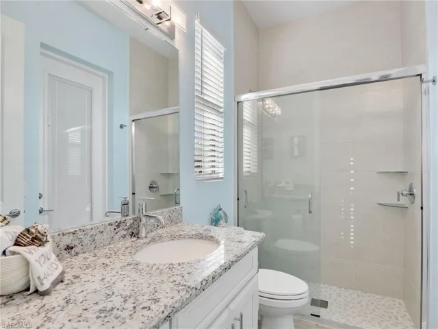Bathroom featuring vanity, toilet, and a shower with shower door