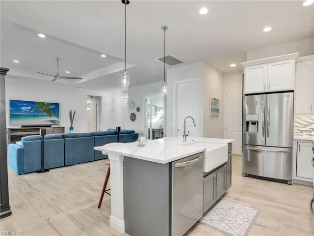 Kitchen featuring sink, tasteful backsplash, a center island with sink, appliances with stainless steel finishes, and white cabinets