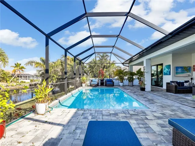 View of pool featuring a patio, a water view, an outdoor hangout area, and glass enclosure