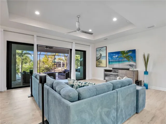 Living room featuring a tray ceiling, light hardwood / wood-style flooring, and ceiling fan