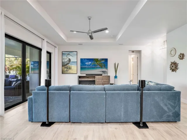 Living room featuring french doors, ceiling fan, a raised ceiling, and light hardwood / wood-style flooring