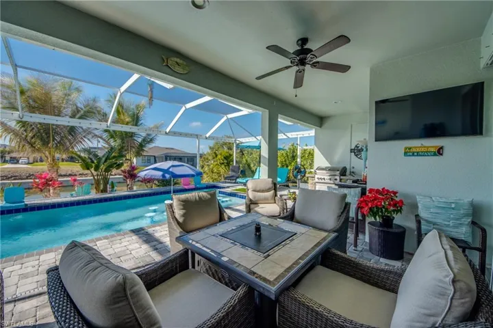 View of patio / terrace featuring a sunroom, an outdoor pool, glass enclosure, a ceiling fan, and grilling area
