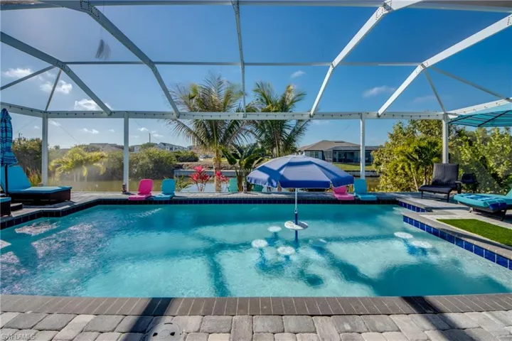 Outdoor pool with glass enclosure, a sunroom, and a patio