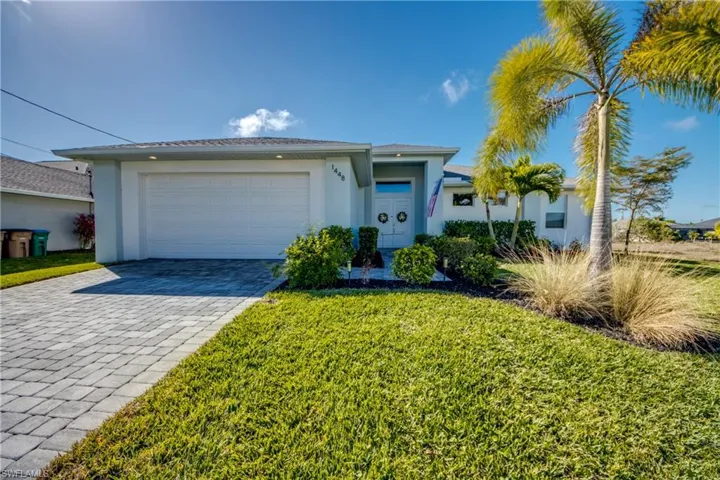 Ranch-style house featuring stucco siding, decorative driveway, a garage, and a front lawn