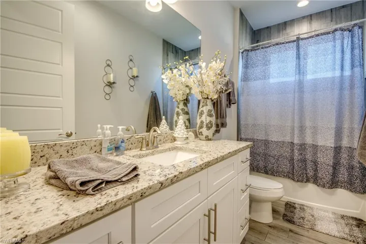 Bathroom with vanity, light wood-style floors, shower / tub combo with curtain, and recessed lighting