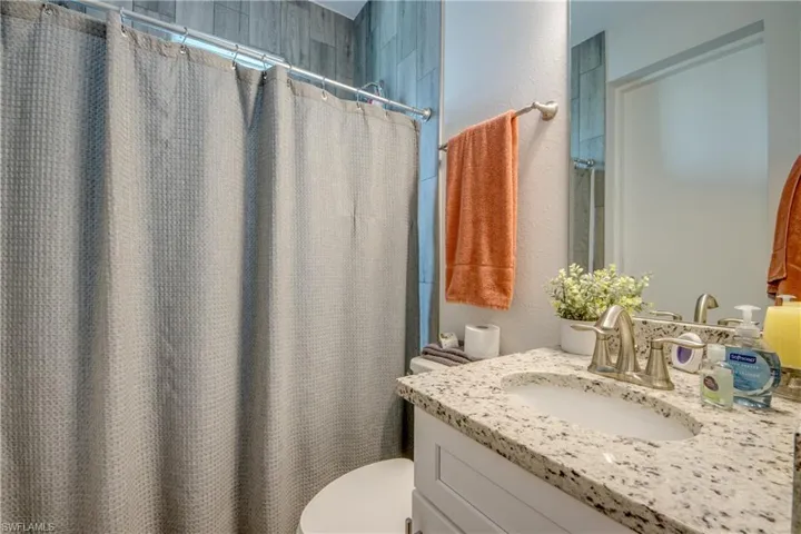 Bathroom featuring vanity, a textured wall, and a shower with shower curtain