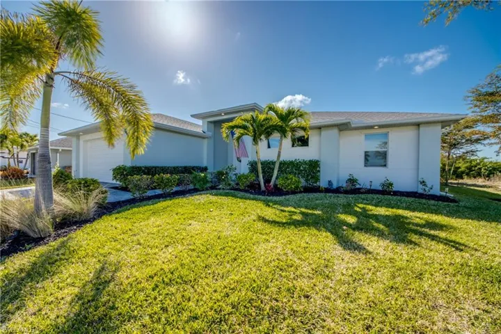 View of front of house with a garage, stucco siding, and a front yard