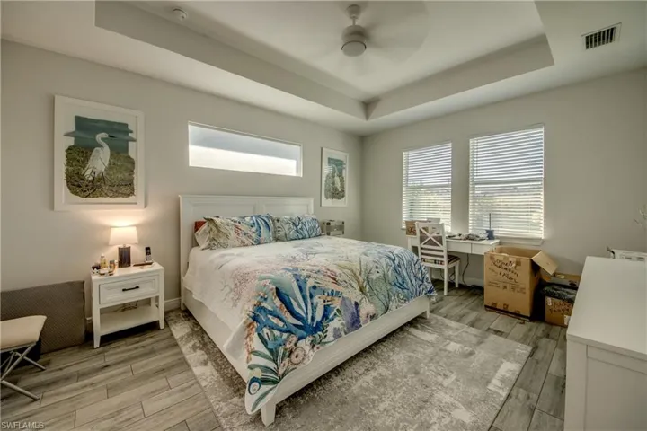 Bedroom featuring wood tiled floors, a tray ceiling, and a ceiling fan