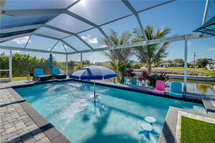Outdoor pool featuring glass enclosure, a sunroom, and a patio