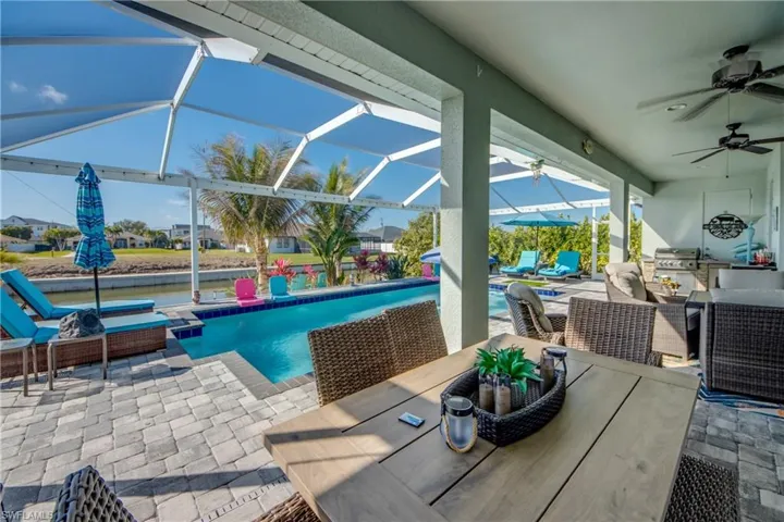 View of patio featuring an outdoor pool, a ceiling fan, a sunroom, glass enclosure, and an outdoor kitchen / dining area