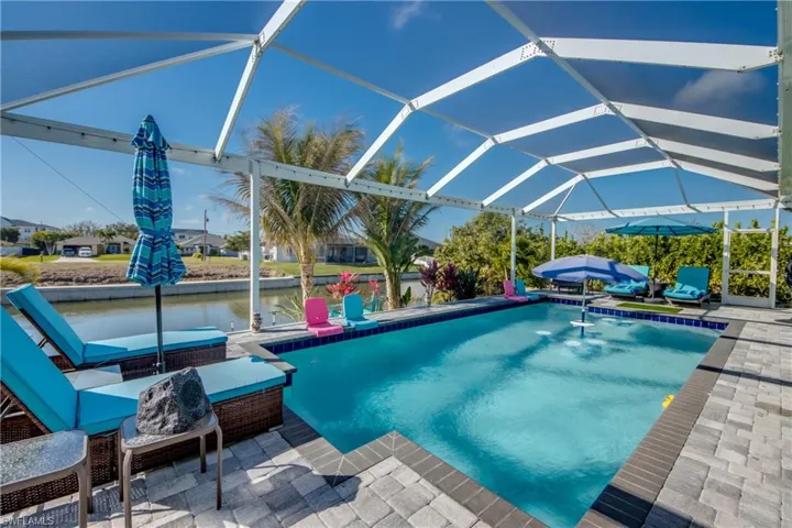 Outdoor pool featuring a lanai, a patio, a water view, and a sunroom