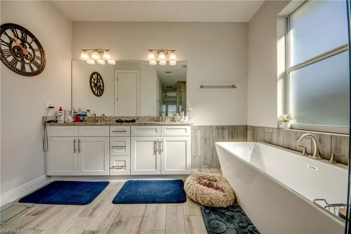 Bathroom with double vanity, a freestanding bath, and light wood finished floors
