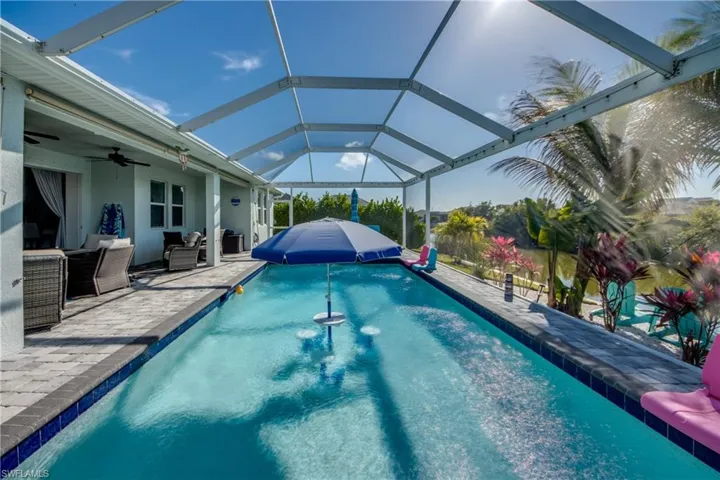 Swimming pool with a sunroom, a patio area, an outdoor hangout area, and a lanai