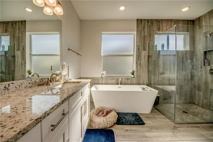 Bathroom featuring vanity, a shower stall, a soaking tub, recessed lighting, and wood tiled floors