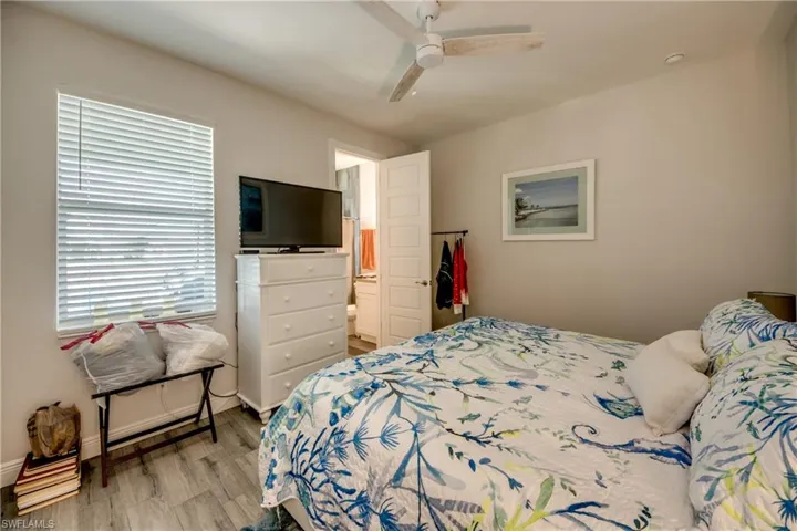 Bedroom with light wood-style flooring, a ceiling fan, and ensuite bathroom