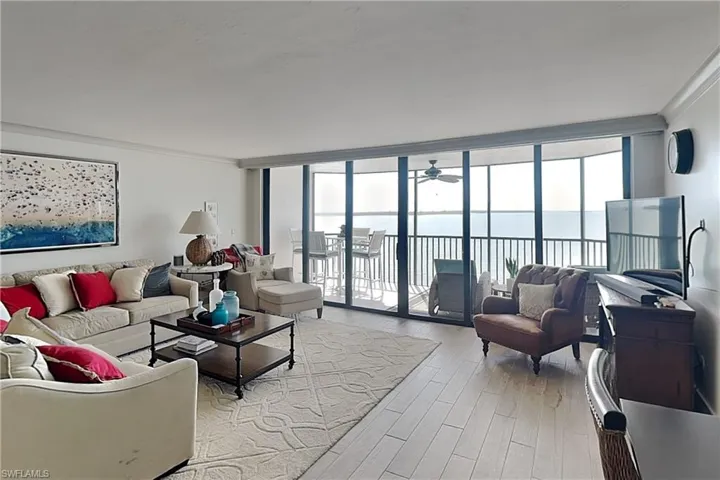 Expansive living area featuring light wood-finish flooring and a private balcony overlooking water