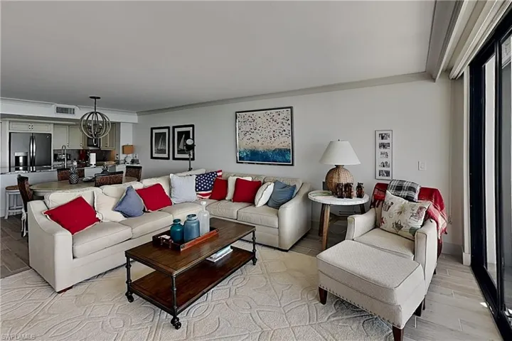 Open-concept living area with light-toned walls, wood-finish flooring, and a large area rug