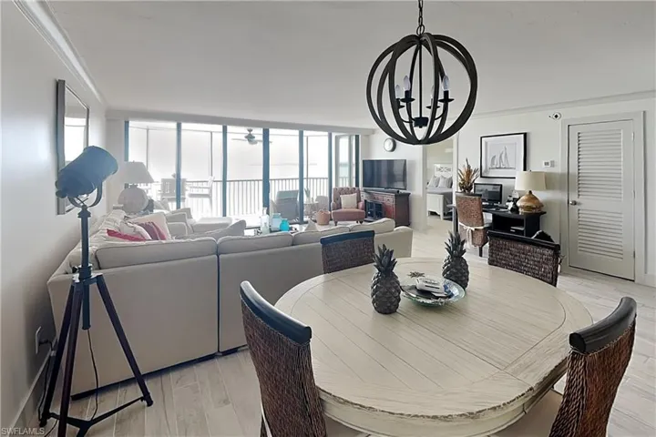 Open-concept living space featuring wood-finish flooring, a contemporary spherical chandelier, and expansive windows