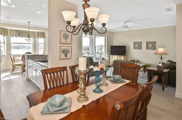 Dining room with ornamental molding, a chandelier, light wood-style flooring, and ceiling fan