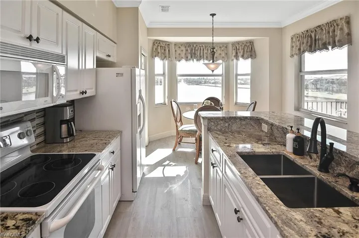 Kitchen with white cabinets, white appliances, light stone countertops, pendant lighting, and light wood-type flooring