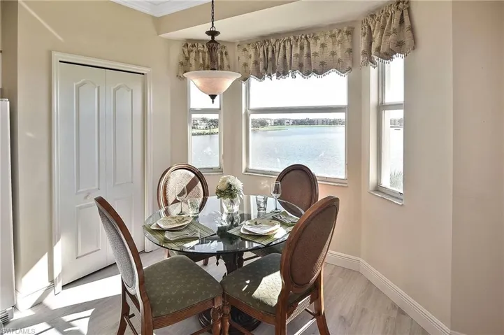 Dining room featuring wood finished floors, ornamental molding, and a water view