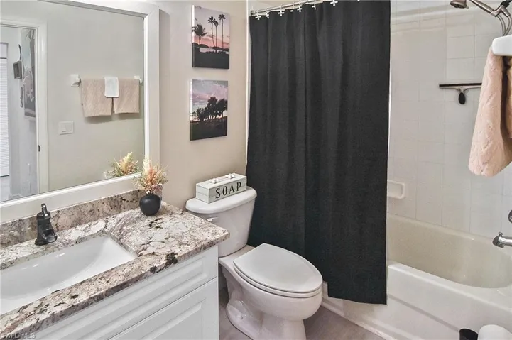 Bathroom featuring shower / bathtub combination with curtain and vanity