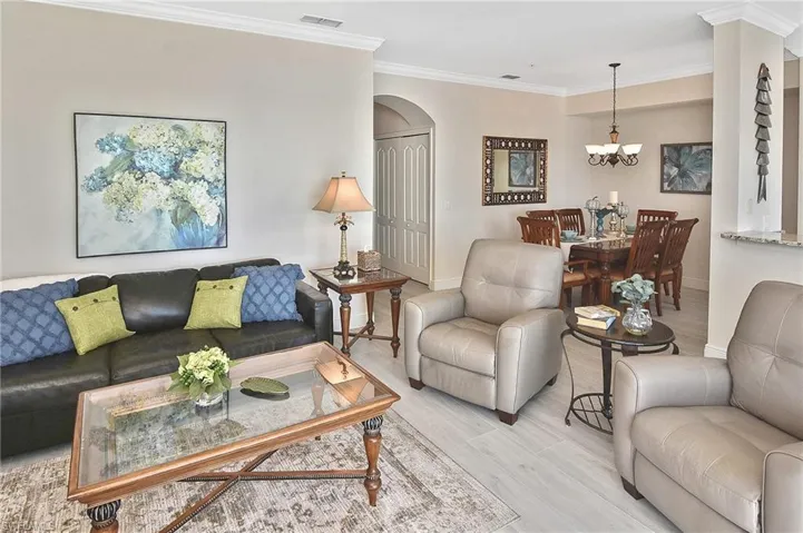 Living room with ornamental molding, arched walkways, and wood finished floors