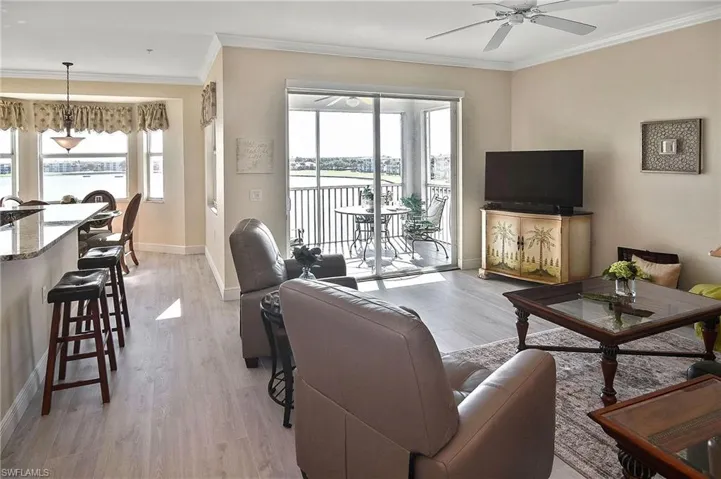 Living area featuring crown molding, light wood-style floors, healthy amount of natural light, and a ceiling fan