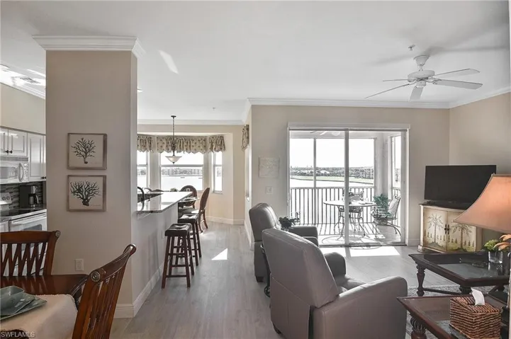 Living area featuring crown molding, light wood-style flooring, and a ceiling fan