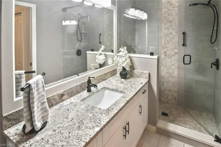 Full bathroom with vanity, light tile patterned floors, and a stall shower