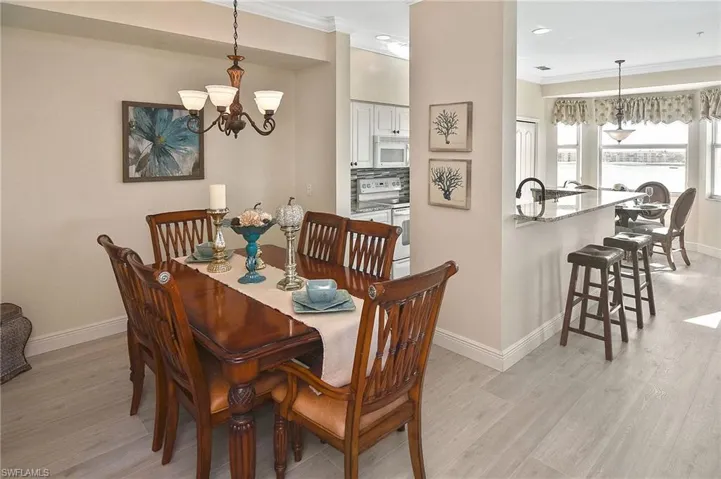 Dining space with light wood finished floors, a chandelier, and crown molding