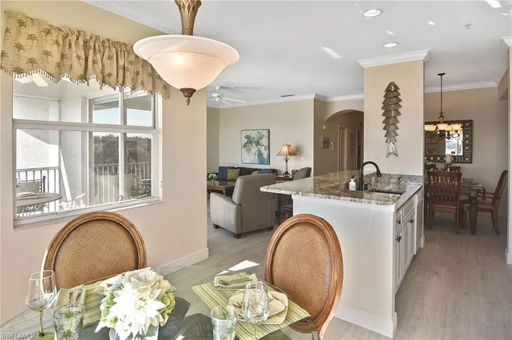 Dining area featuring crown molding, arched walkways, light wood finished floors, recessed lighting, and ceiling fan