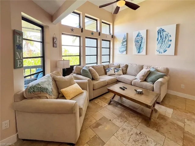 Living room featuring ceiling fan, light tile patterned flooring, and a high ceiling