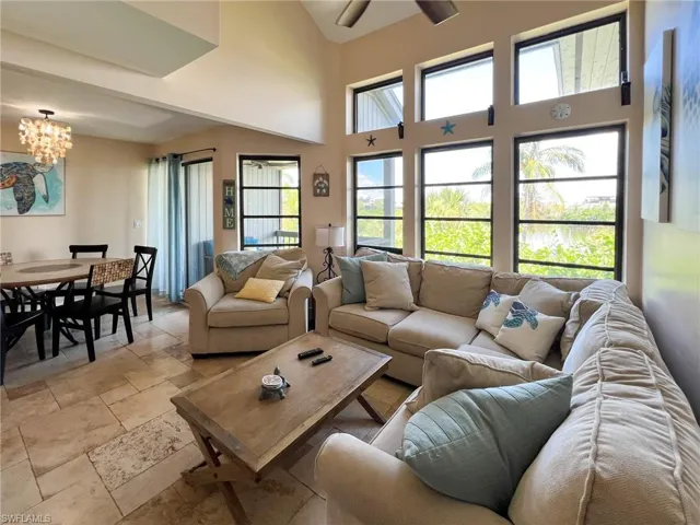 Tiled living room featuring a towering ceiling and ceiling fan with notable chandelier