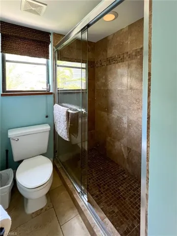 Bathroom with tile patterned floors, an enclosed shower, and toilet