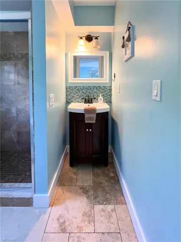 Bathroom featuring a tile shower, vanity, and tile patterned floors