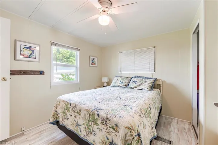 Bedroom featuring light wood-type flooring, ceiling fan, and wood walls