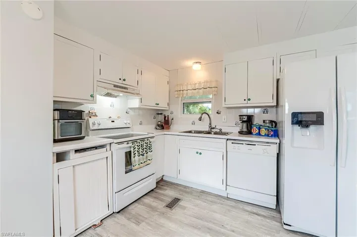 Kitchen with white appliances, white cabinets, light countertops, and light wood-type flooring