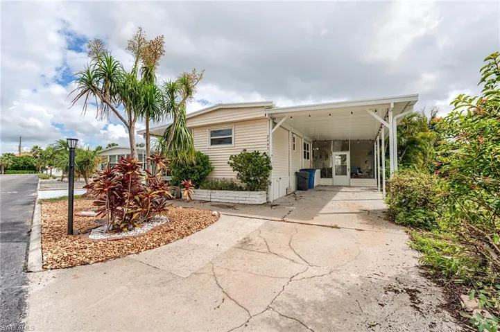 View of property exterior with concrete driveway, a carport, and a patio