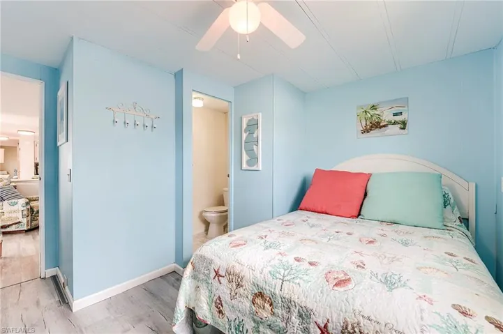 Bedroom with wood finished floors, ceiling fan, and ensuite bath