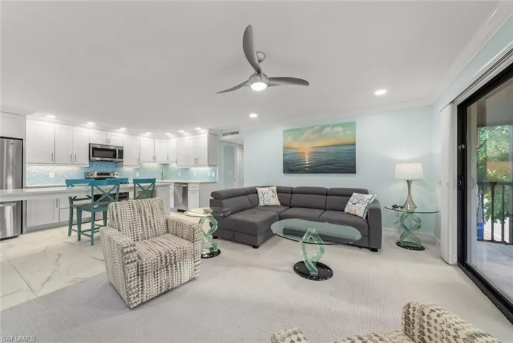 Living area with crown molding, recessed lighting, ceiling fan, and light marble finish floors