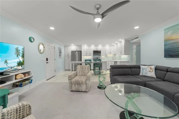Living room featuring recessed lighting, ornamental molding, and ceiling fan