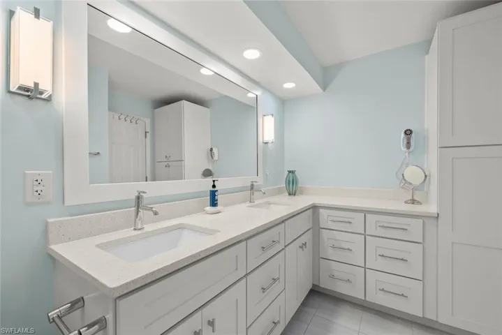 Full bathroom with double vanity, recessed lighting, and light tile patterned floors